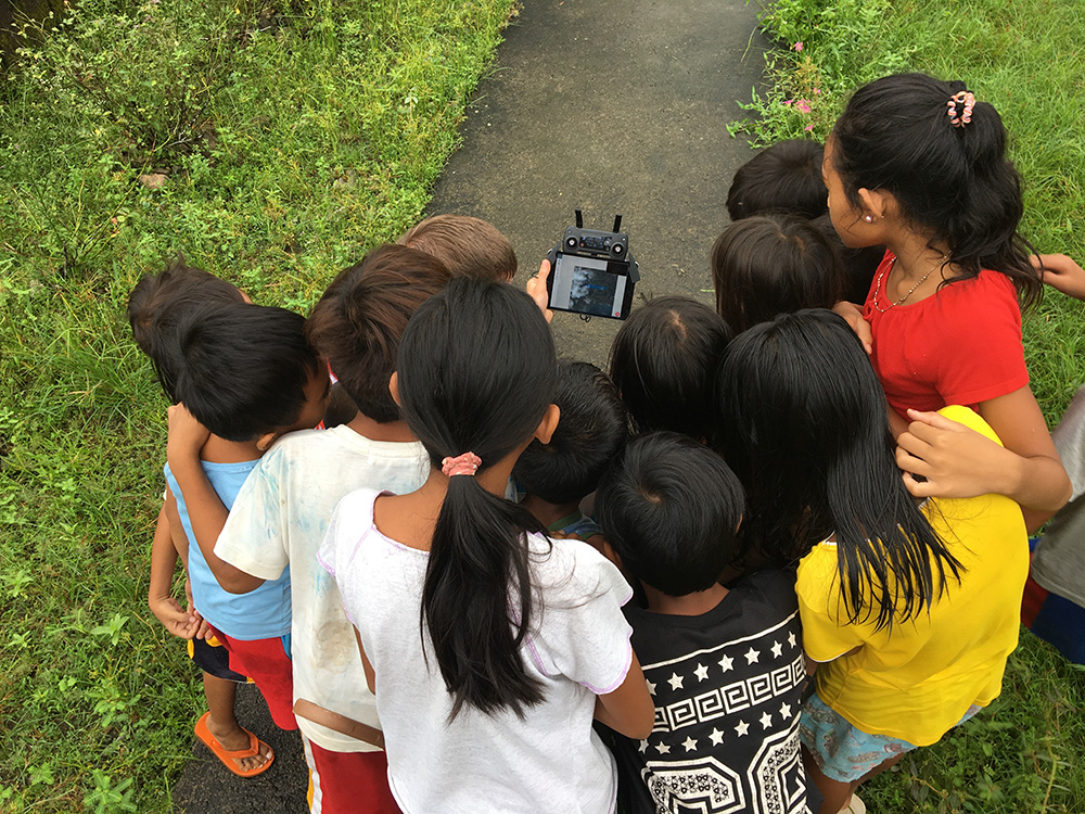 A crowd of interested children observe the progress of a drone mapping mission in Leyte, Philippines.